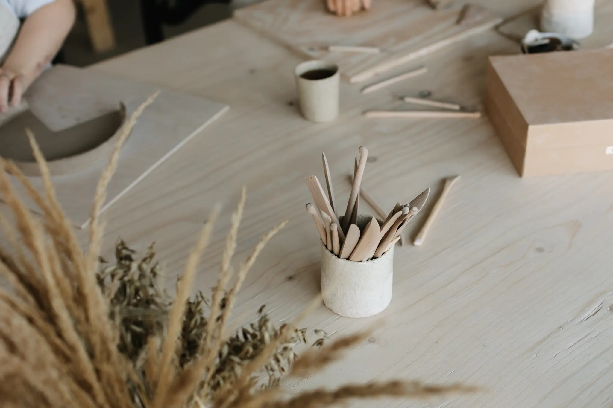 Lähikuva herkullisesta täytekakusta ja käsintehdyistä keraamisista mukeista studion oranssilla tiilitasolla. Tunnelmallinen kuva kurssin kahvi- ja herkkutarjoilusta.